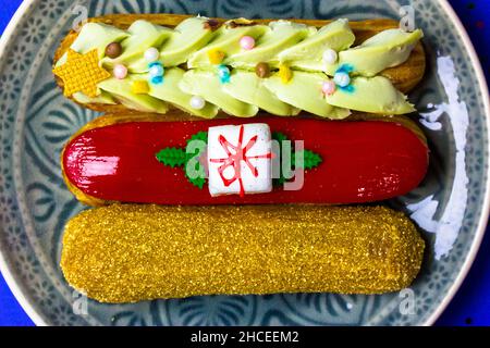 Festively decorated eclairs in New Year's style 2022 lying on round gray plate. Stock Photo
