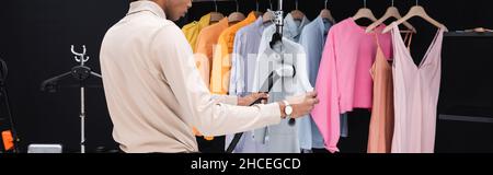 cropped view of african american stylist using steamer while cleaning clothes in dressing room, banner Stock Photo