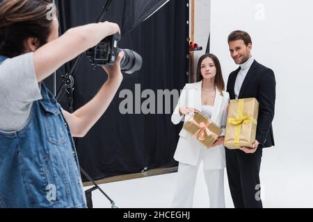 stylish models holding gift boxes while posing at photographer in photo studio Stock Photo