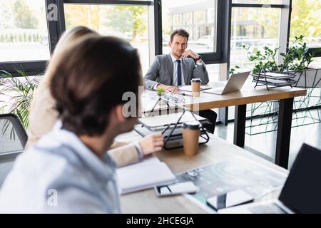 young business people working in office near devices and documents on desks, blurred foreground Stock Photo