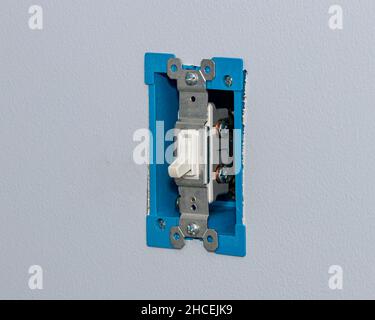 White electrical light switch and wiring in wall. DIY home maintenance, remodeling, and electricity repair concept. Stock Photo