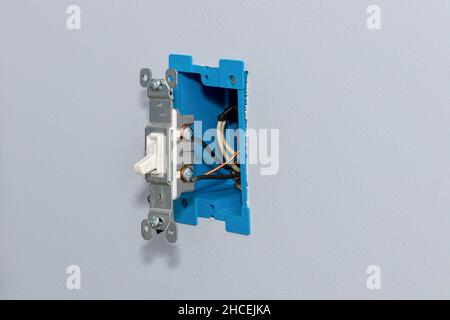 White electrical light switch and wiring in wall. DIY home maintenance, remodeling, and electricity repair concept. Stock Photo