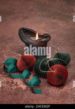 Thick black candle and four paper baubles Stock Photo