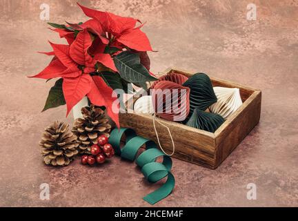 Red Poinsettia and paper baubles in wooden box Stock Photo
