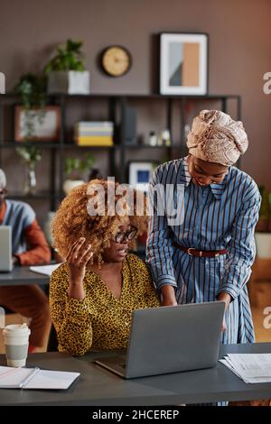 Businesswoman using laptop together with her colleague, they working over online presentation at office Stock Photo