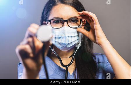 female doctor in a medical mask holds a stethoscope. Concept medicine image, level of medicine, virus, epidemic corona or covid-19 Stock Photo