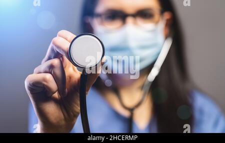 female doctor in protective mask holding stethoscope and looking at camera. Concept medicine image, level of medicine, virus, epidemic corona or covid Stock Photo