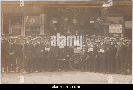 1913 Black Country Strike: In May 1913 a procession of strikers from Handsworth & Oldbury travelled to Saltley to try to get support from local carriage workers. This photograph shows a large group of men demonstrating in the street. Two men are standing on a cart which has 'Uncle Joe of Saltley' written on it. Some men are holding up collection boxes with 'Railway carriage and waggon workers strike fund' written on. The shops in the background include Hewes and Edwards. A sign for 'Stephenson Place' can be seen on the streetlamp. The photographic postcard was sold by Ridge of Saltley Stock Photo