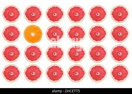 Rows of grapefruit slices and only one orange slice isolated on a white background Stock Photo