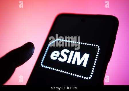 In this photo illustration, eSIM word, name of an embedded integrated programmable SIM card that is embedded directly into a mobile phone, is seen on a smartphone. Stock Photo