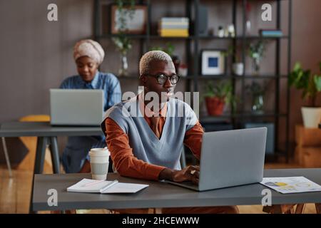 African young businessman sitting at his workplace at office and working on laptop Stock Photo