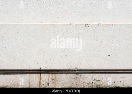 White stucco wall with rusty metal pipe background Stock Photo