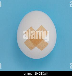 medical plaster is isolated on white background, two plasters forming cross on egg, close up, creative easter concep Stock Photo