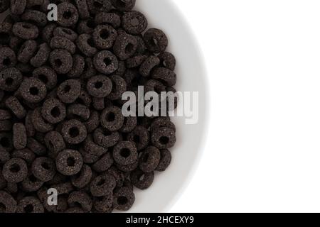 heap of black cereal rings isolated on white background, delicious and useful rings breakfast cereal in bowl, top view closeup Stock Photo