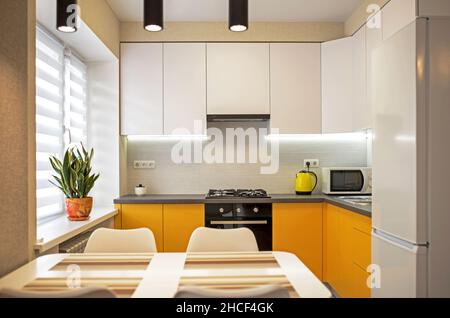 Part of the interior of the living room with a wardrobe and kitchen in orange tones Stock Photo