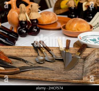 table with medieval spoons and knives, on the table ceramic plates, jugs and bread, Stock Photo