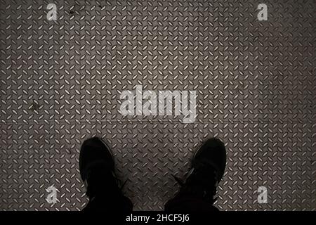 Two feet of an unknown person on a metal background and with a large copy space Stock Photo