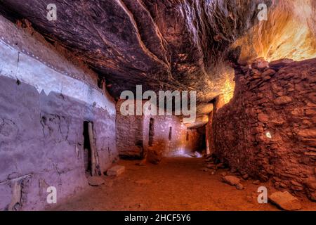 Indirect bounce light creates interesting colors in an ancient interior hallway below a sloping layered cliff wall in the late 13th century Moon House Stock Photo