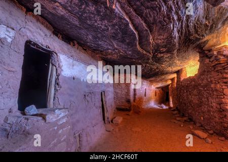 Indirect bounce light creates interesting colors in an ancient interior hallway below a sloping layered cliff wall in the late 13th century Moon House Stock Photo