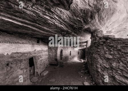 An interior hallway below a sloping layered cliff wall in the Moon House in McCloyd Canyon, Bears Ears National Monument. (Black & White) Stock Photo