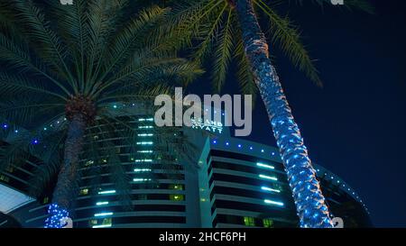 Low angle of the palm trees with decorative lights against the backdrop of the hotel by night Stock Photo