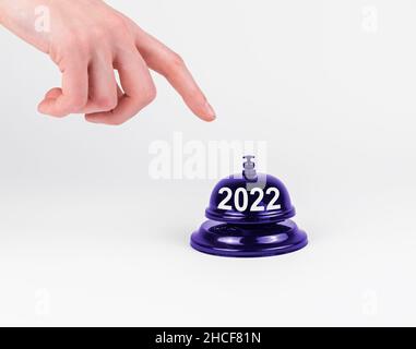 2022 New Year start concept. Hand finger pressing desk bell button. Stock Photo