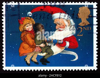 GREAT BRITAIN - CIRCA 1997: a stamp printed in the Great Britain shows Christmas Crackers, Santa as Man in Moon Sharing Cracker with Two Children, cir Stock Photo