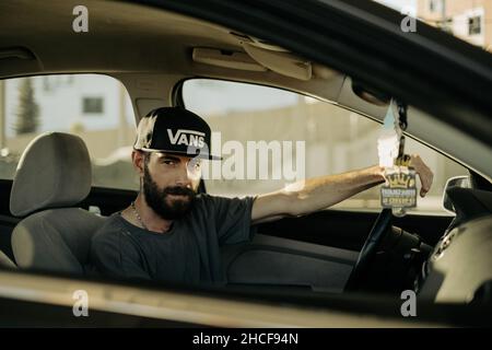 Man confidently posing in the car wearing Vans baseball cap Stock Photo