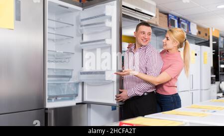 Couple chooses refrigerator in shop of household appliances Stock Photo