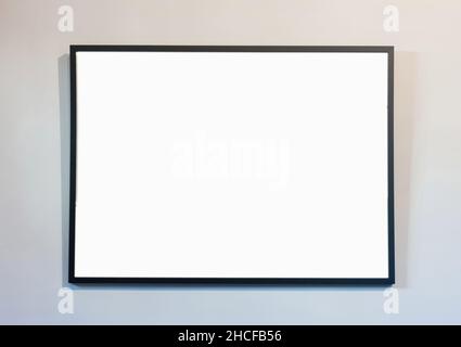 Empty frame on white wall background, copy space. Poster mockup. Black, modern, minimal border for text, ad, product presentation Stock Photo