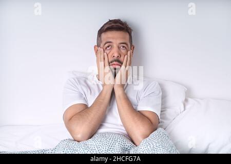 Stressed and depressed man lying in the bed. Bad mood and bad morning. Stock Photo