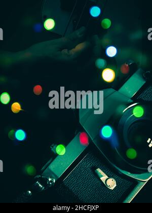 Composite image of analogue film camera, bass guitar playing and bokeh of multi-coloured lights Stock Photo