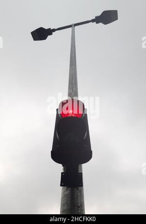 There is a two-color traffic light on the street lamp post, which is lit in red. Photographed from below Stock Photo