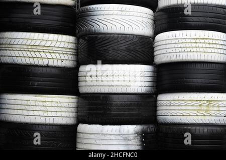 Stacks of black and white old tires, forming a checkered pattern. Landscape orientation. Stock Photo