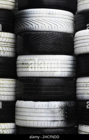 Stacks of black and white old tires, forming a checkered pattern. Portrait orientation. Stock Photo