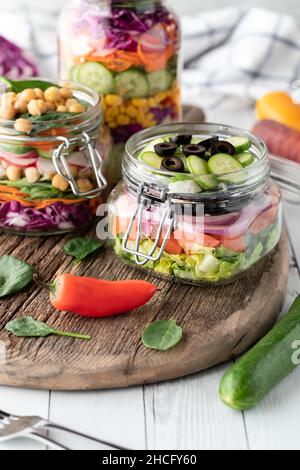 Jars filled with freshly made salad on a rustic wooden board. Stock Photo