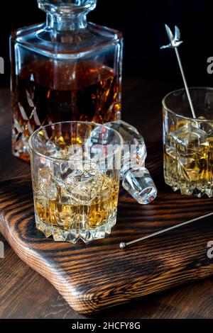 Glasses of whiskey with ice and a full decanter of whiskey in behind. Stock Photo