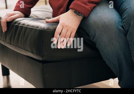 Caucasian woman in the store chooses for buy an ottoman made of brown leather Stock Photo