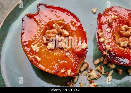 Macro baked quince with honey, walnut and cinnamon on green plate. Selective focus Stock Photo