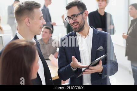 colleagues discussing current tasks standing in the office Stock Photo