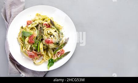 Pasta with asparagus and prosciutto on gray background. Traditional Italian Food concept. Top view, flat lay, copy space Stock Photo