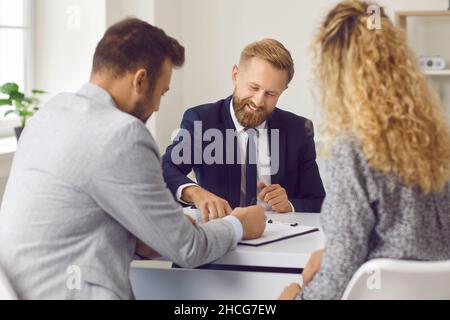Young couple buying or renting house, meeting with real estate agent and signing papers Stock Photo