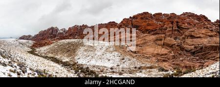 Panoramic shot of a snowy mountainous area under the cloudy sky Stock Photo