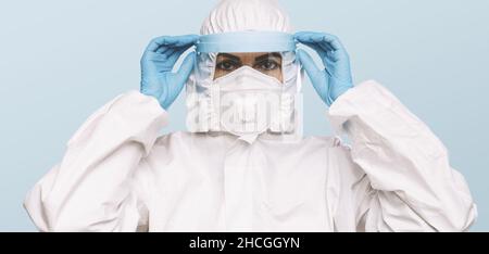 Female Doctor or Nurse Wearing latex protective gloves and medical Protective Mask with shield and glasses on face. Protection for Coronavirus COVID-1 Stock Photo