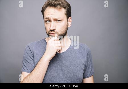 thoughtful man who looks away touching his chin and weighs the pluses and minuses of the offer Stock Photo