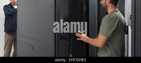 Technicians team updating hardware inspecting system performance in super computer server room or cryptocurrency mining farm. Stock Photo