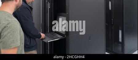 Technicians team updating hardware inspecting system performance in super computer server room or cryptocurrency mining farm. Stock Photo