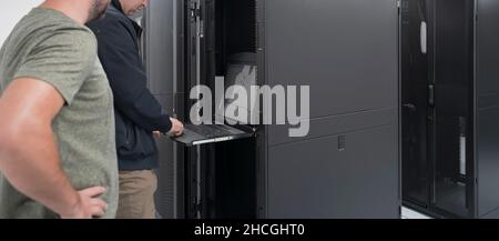 Technicians team updating hardware inspecting system performance in super computer server room or cryptocurrency mining farm. Stock Photo