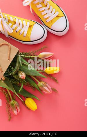 Sneakers and paper bag with flowers on pink background Stock Photo