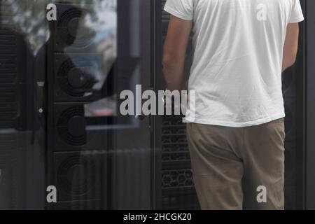 Data Center Engineer Using Laptop Computer. Server Room Specialist Facility with Korean Male System Administrator Working with Data Protection Network Stock Photo